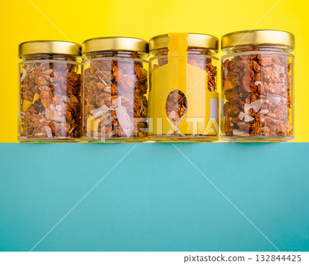 Glass jars filled with granola on a colorful background Glass jars filled with granola on a colorful background 132844425