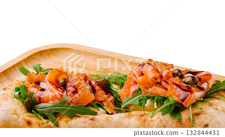 Gourmet flatbread topped with smoked salmon and arugula served on a wooden tray Gourmet flatbread topped with smoked salmon and arugula served on a wooden tray 132844431