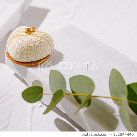 A beautifully designed dessert sits atop white paper with gentle lighting 132844440