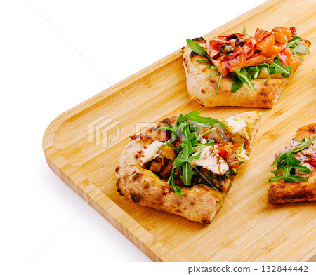 Delicious flatbreads topped with fresh ingredients on a wooden board Delicious flatbreads topped with fresh ingredients on a wooden board 132844442