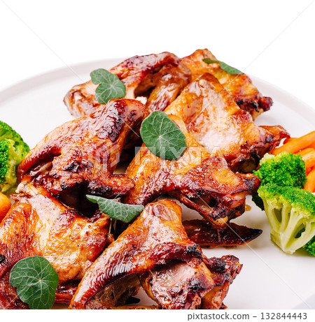 Grilled chicken wings garnished with herbs and fresh vegetables for a meal Grilled chicken wings garnished with herbs and fresh vegetables for a meal 132844443