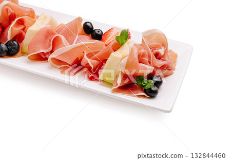 Delicious platter of cured meats and fresh fruits served elegantly 132844460