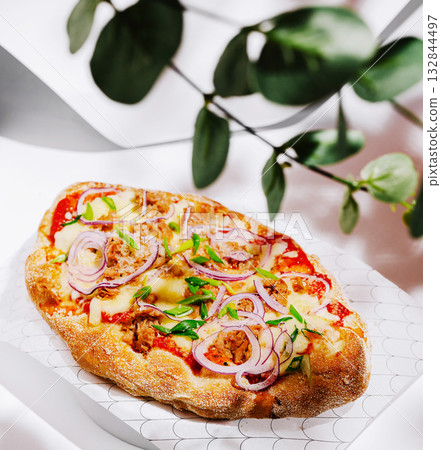 Delicious flatbread topped with cheese, vegetables, and herbs in a restaurant Delicious flatbread topped with cheese, vegetables, and herbs in a restaurant 132844497
