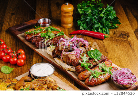 Grilled meats served on a wooden platter with garnishes and sides 132844520