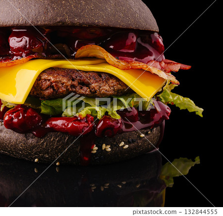 Unique black burger with cheese and bacon on a dark background Unique black burger with cheese and bacon on a dark background 132844555