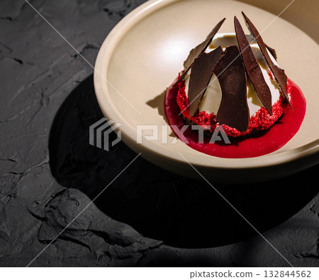 Unique dessert presentation featuring layers of red and chocolate elements Unique dessert presentation featuring layers of red and chocolate elements 132844562