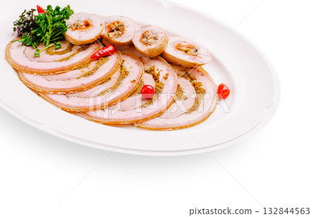 Sliced meat roll served on a white platter with herbs and chili 132844563