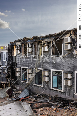 Bila Tserkva, Kyiv region, Ukraine - 09.06.2025: War. The aftermath of Russian airstrikes on a peaceful Ukrainian city. Burned brick building with charred upper floor, broken roof, and debris. 132845449
