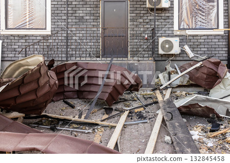 Ground level view of structural damage collapsed roofing and scattered debris lie before dark brick facade with door and AC units, documenting impact of failure or disaster on built environment. Ground level view of structural damage collapsed roofing and scattered debris lie before dark brick facade with door and AC units, documenting impact of failure or disaster on built environment. 132845458