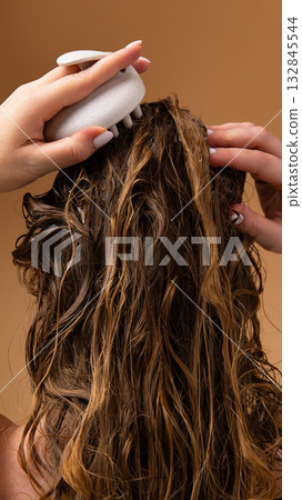 Female model performing scalp massage with brush during home hair washing routine 132845544