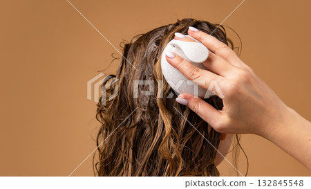Scalp massage with exfoliating brush on wet hair during washing routine 132845548