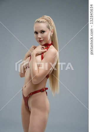 Woman poses in studio wearing leather belts with confidence and grace Woman poses in studio wearing leather belts with confidence and grace 132845634