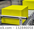 Large yellow boxes moving on a conveyor belt in a modern warehouse setting 132846058