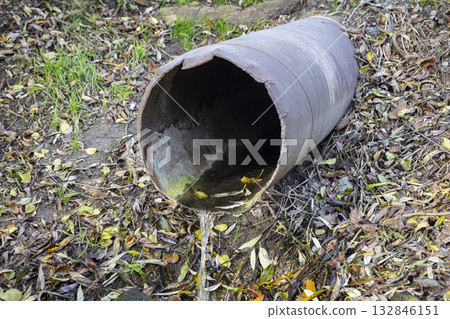 An old iron drain pipe with water leaking out of it 132846151