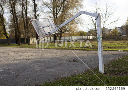 A broken and lopsided basketball hoop stands on an open-air sports court 132846169
