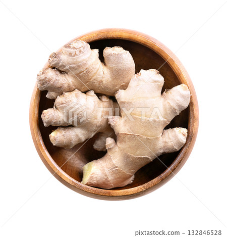 Fresh ginger root, in a white bowl. Juicy and fleshy rhizome of Zingiber officinale, used as fragrant kitchen spice, and in traditional folk medicine. Close-up, from above, isolated over white. Photo 132846528