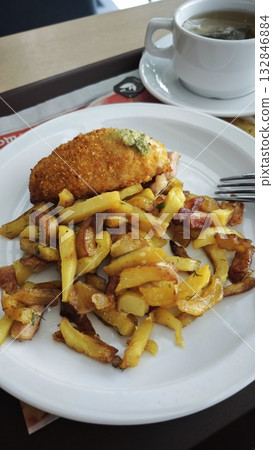 Fried chicken cutlet with herb butter served with crispy golden potato fries on a white plate. Concept of homemade comfort food and casual dining meal 132846884