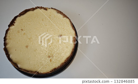 Homemade baked cheesecake with golden crust on a light background. Concept of homemade dessert, baking and sweet indulgence 132846885