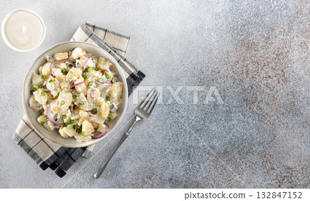 Potato salad with pickled cucumbers and onions. Top view on gray background. Copy space. German, American cuisine. 132847152