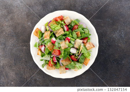 Lebanese Fattoush salad with fresh vegetables and pita on a gray background. Top view. 132847154