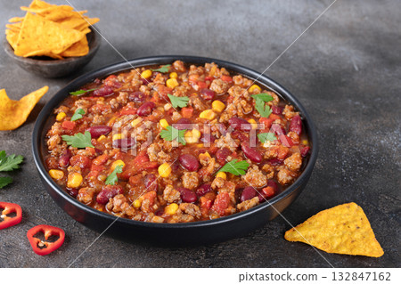 Meat mexican stew with beans, corn and tortilla chips chili con carne on gray background. Tex-Mex cuisine. 132847162