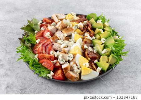 American Cobb salad with tomatoes, bacon, chicken, eggs, avocado, blue cheese on gray background. Top view. Copy space. 132847165