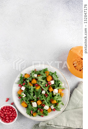 Pumpkin salad with arugula, feta cheese, pomegranate seeds on gray background. Top view. Thanksgiving Dishes. Copy space 132847176