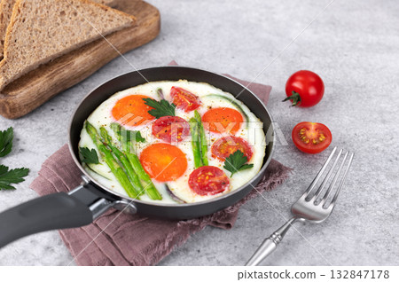 Fried eggs with vegetables asparagus, onions, tomatoes, toast on a gray background. Breakfast. Fried eggs with vegetables asparagus, onions, tomatoes, toast on a gray background. Breakfast. 132847178