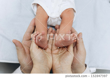 Newborn baby feet in parents hands symbolizing love, care and family protection 132847397