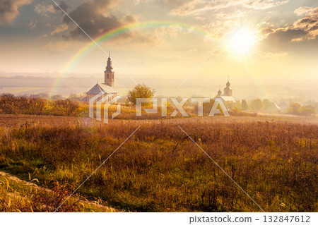 old church in the village in autumn at sunset. view of countryside landscape from a hill in hazy evening light. empty rural fields. pilgrimage storytelling image under the rainbow old church in the village in autumn at sunset. view of countryside landscape from a hill in hazy evening light. empty rural fields. pilgrimage storytelling image under the rainbow 132847612
