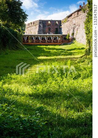 uzhhorod, ukraine - 08 aug 2012: grass in the old castle moat on a sunny afternoon. legendary landmark of transcarpathia under blue sky. medieval stronghold vertical travel background uzhhorod, ukraine - 08 aug 2012: grass in the old castle moat on a sunny afternoon. legendary landmark of transcarpathia under blue sky. medieval stronghold vertical travel background 132847617
