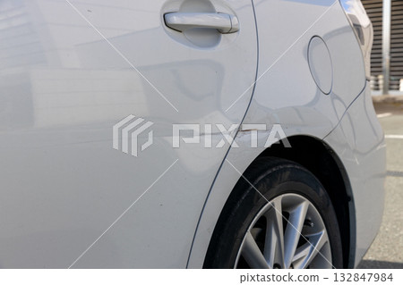 Dents near the rear door of a car 132847984