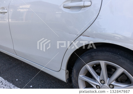 Dents near the rear door of a car 132847987