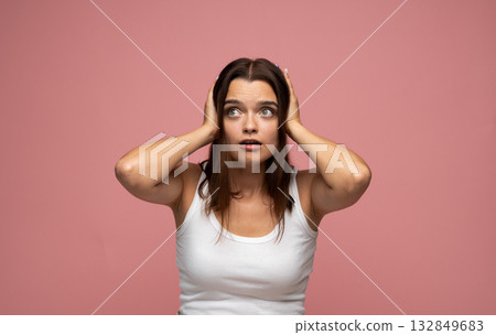 Shocked young woman holding head with both hands expressing surprise or panic 132849683