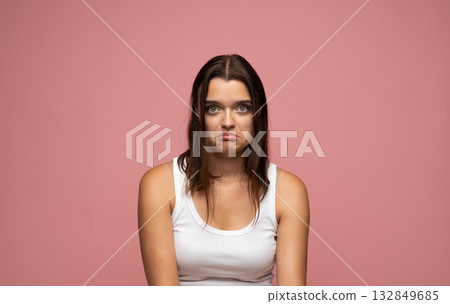 Studio portrait of young woman looking disappointed and upset showing sad face on pink background Studio portrait of young woman looking disappointed and upset showing sad face on pink background 132849685