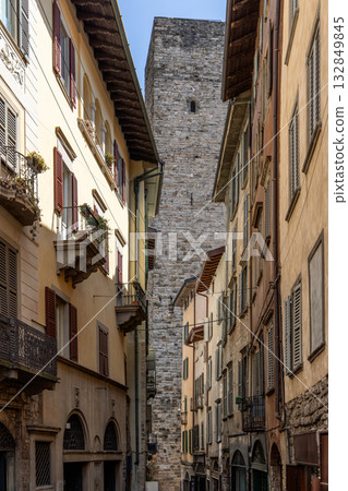 Narrow street in Bergamo Upper Town with warm facades and shutters leading toward stone tower Narrow street in Bergamo Upper Town with warm facades and shutters leading toward stone tower 132849845
