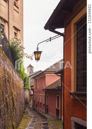 Charming alley on San Giulio Island with pastel walls vintage lantern and stone bell tower view Charming alley on San Giulio Island with pastel walls vintage lantern and stone bell tower view 132849881