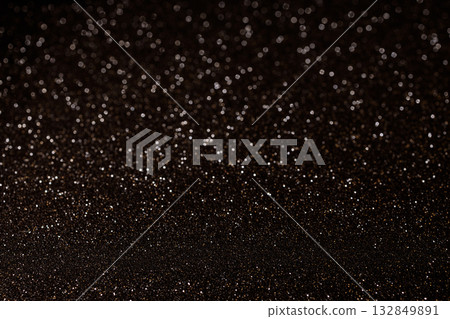 Golden glitter scattered on dark black background creating dramatic starry elegant design effect 132849891