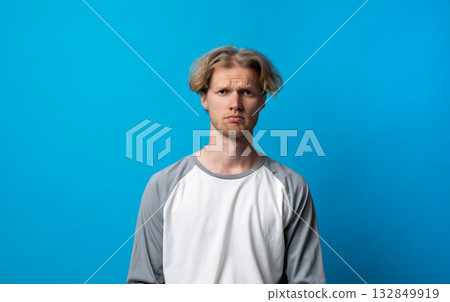Sad man in gray and white shirt looking disappointed on bright blue background 132849919