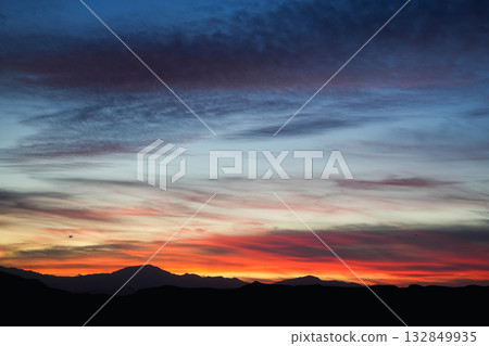 Vivid sunset sky over dark mountain silhouette with colorful clouds and gradient light in evening 132849935