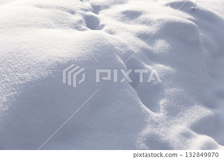 Snowy ground surface with soft hills and sunlight reflections in winter 132849970
