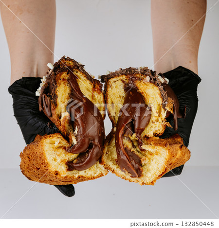 Hands in gloves breaking chocolate filled Christmas panettone, rich festive dessert Hands in gloves breaking chocolate filled Christmas panettone, rich festive dessert 132850448