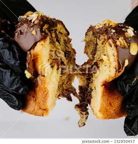 Hands tearing Christmas panettone with gooey nut chocolate filling, festive dessert Hands tearing Christmas panettone with gooey nut chocolate filling, festive dessert 132850457