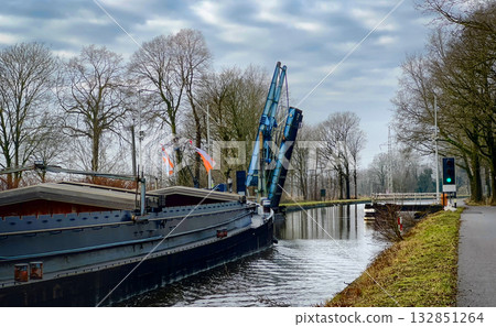 A picturesque canal boat featuring a crane gracefully floating along the scenic waterway A picturesque canal boat featuring a crane gracefully floating along the scenic waterway 132851264