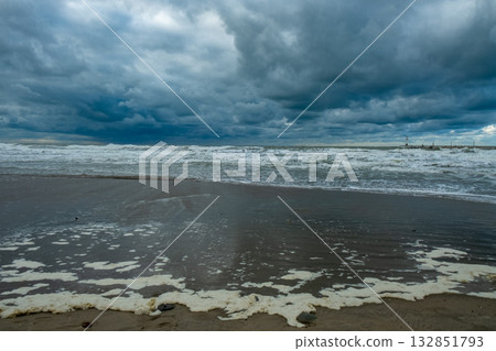 tempest over shoreline and surf, intense weather scenario with turbulent surf and moist beach 132851793