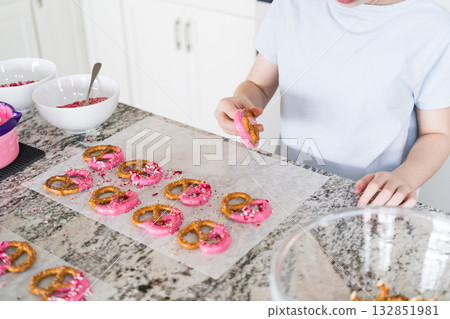 Freshly dipped and still glistening, these crunchy pretzels are lovingly adorned with pink chocolate and a scattering of colorful sprinkles, promising a feast for the senses. 132851981