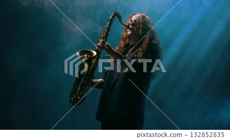 Saxophonist performing in blue light haze with emotional energy and deep focus Saxophonist performing in blue light haze with emotional energy and deep focus 132852835