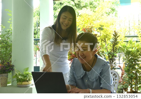Asian elder woman and daughter enjoy working latop computer in front of home Asian elder woman and daughter enjoy working latop computer in front of home 132853054