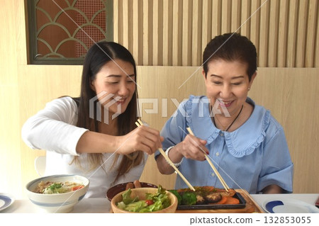 Asian elder woman and daughter have eating Japanese food for lunch by chopsticks in restaurant Asian elder woman and daughter have eating Japanese food for lunch by chopsticks in restaurant 132853055