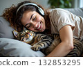 Shot of pretty young woman listening to music and relaxing while sitting on sofa at home. Teenager girl with cat and dog relaxed on couch 132853295